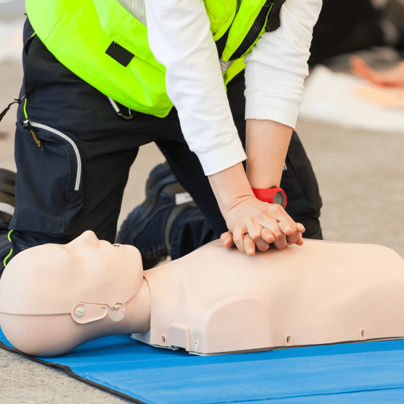 A trainee, giving CPR to a dummy.