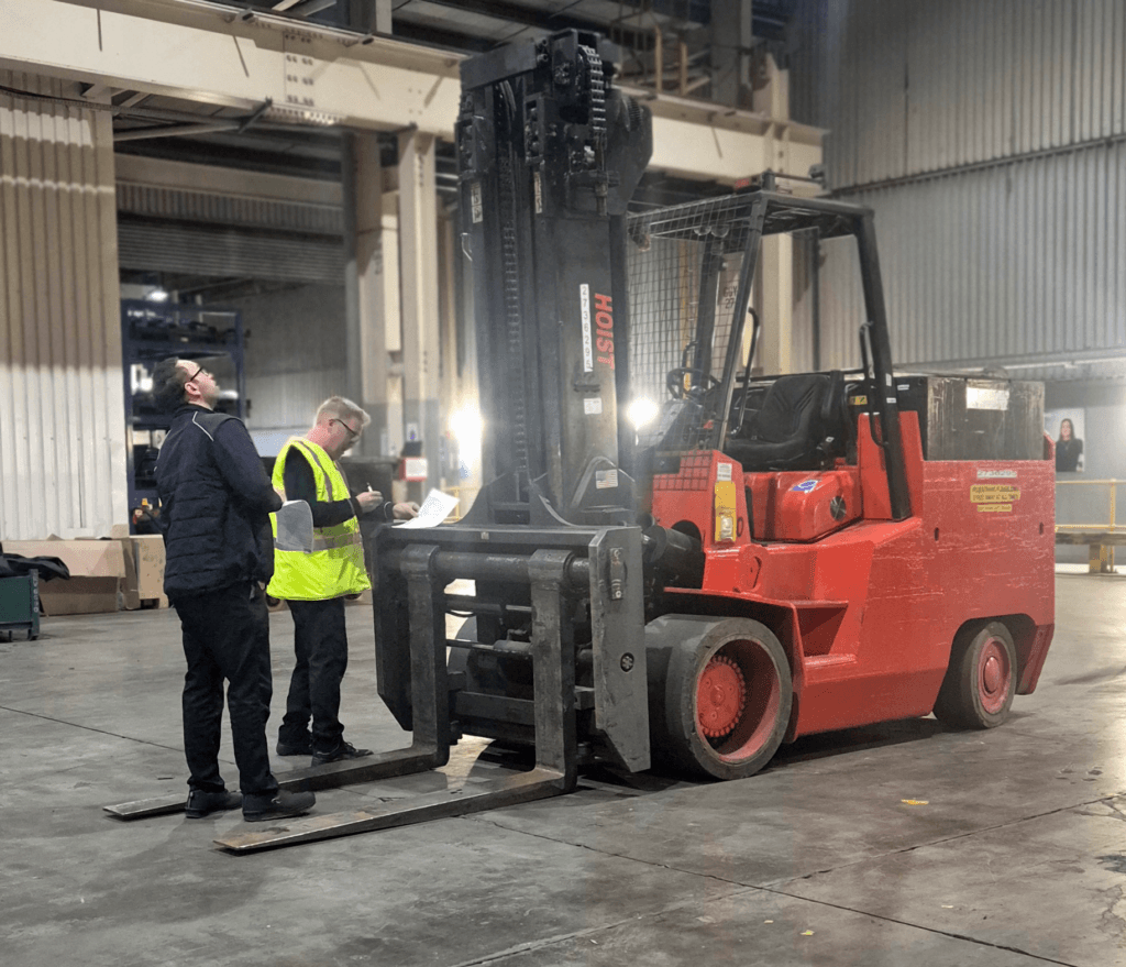 Trainer stood in front of a forklift.